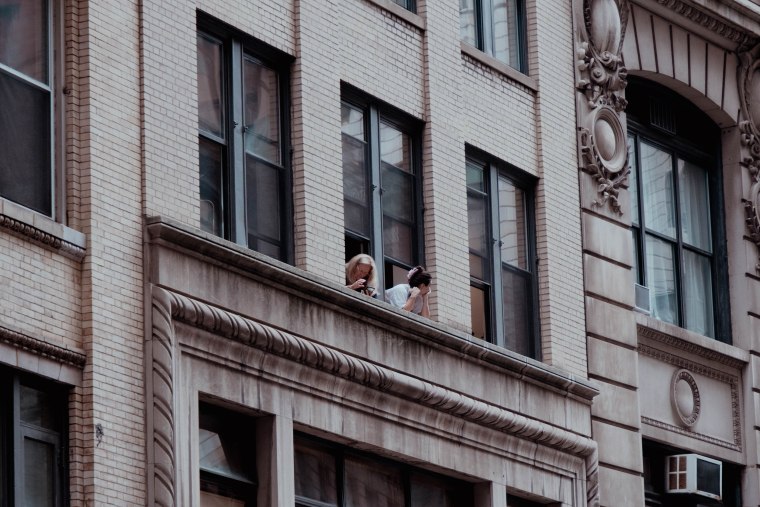 Spectators peer out of windows on Maiden Lane hoping to see the festivities. 