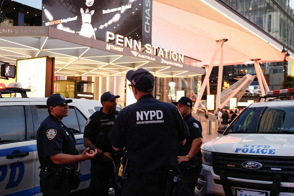 Four law enforcement agents outside Penn Station at dusk. (John Lamparski / AFP via Getty Images)