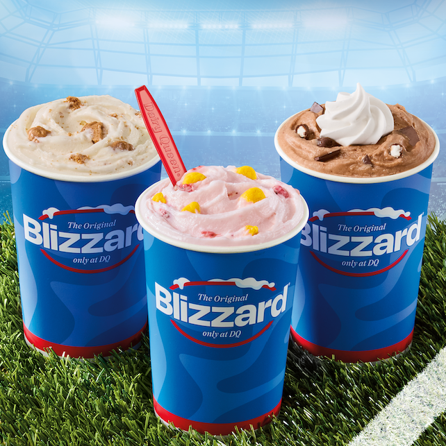 Three Dairy Queen Blizzard cups with different ice cream flavors on grass in a stadium setting. Three Dairy Queen Blizzard cups with different ice cream flavors on grass in a stadium setting.