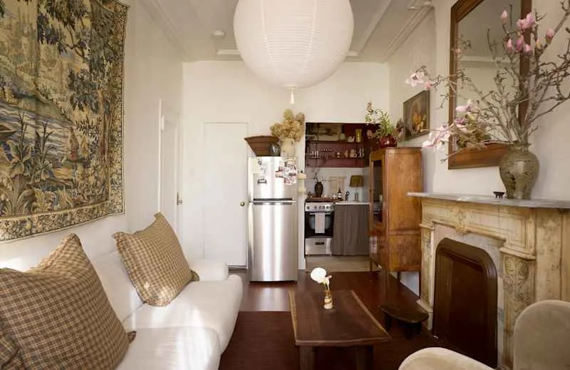 Cozy living space featuring a white sofa with plaid cushions, a wooden coffee table, and a vintage fireplace.