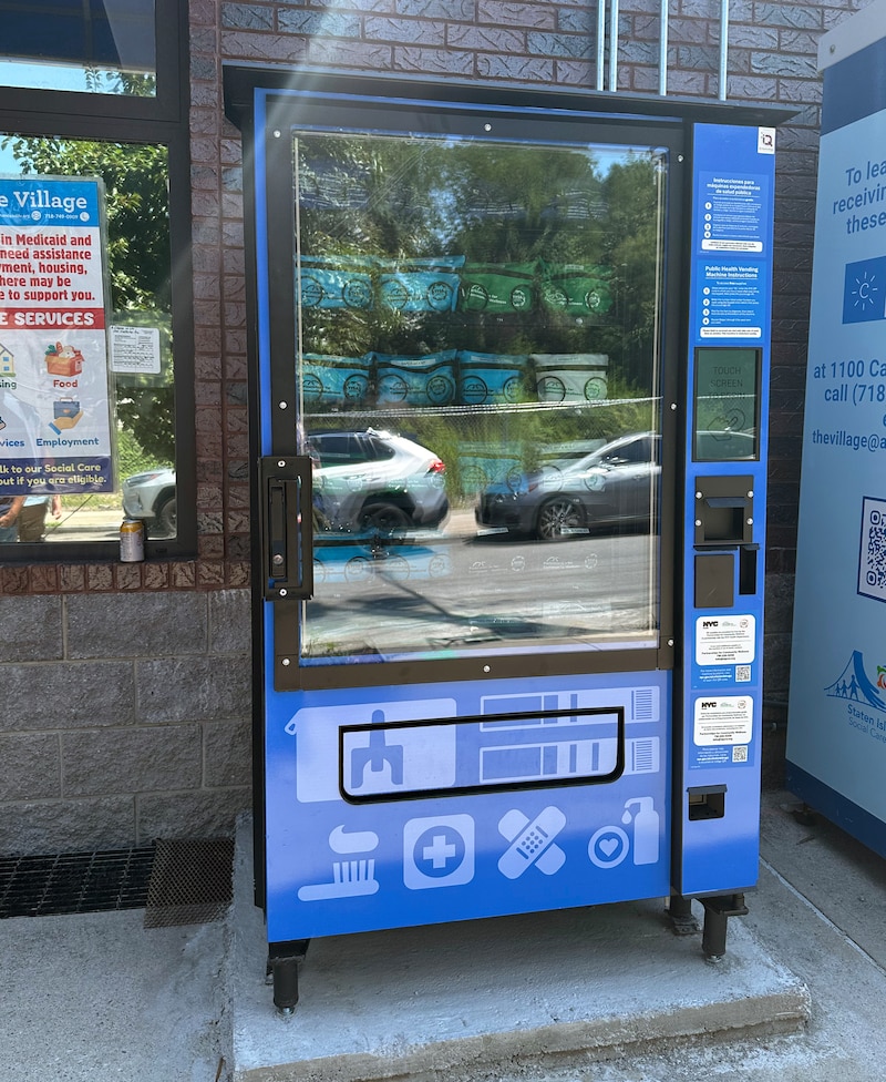 A photograph of a blue and black vending machine standing outside of a building.