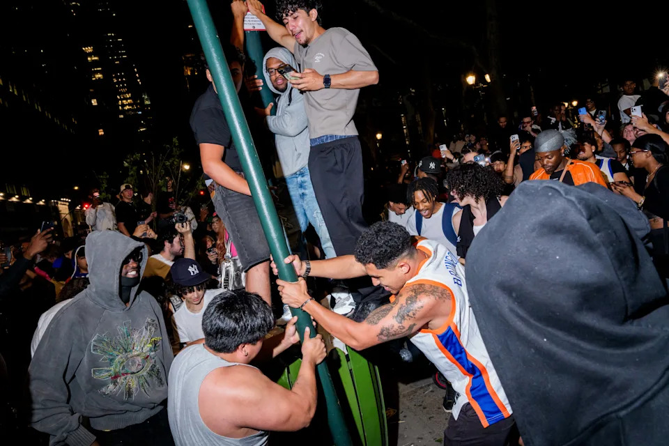 NEW YORK, NEW YORK - JUNE 8: New York Knicks fans try to pull down a street sign outside of a watch party at Bryant Park for Game 3 of the NBA Finals between New York Knicks and San Antonio Spurs on June 8, 2026 in New York City. The New York City Police Department and Secret Service cancelled an NBA Finals watch party near Madison Square Garden, with fans advised to arrive at least two hours before Monday's game due to heightened security for U.S. President Donald Trump's attendance. (Photo by Adam Gray/Getty Images)