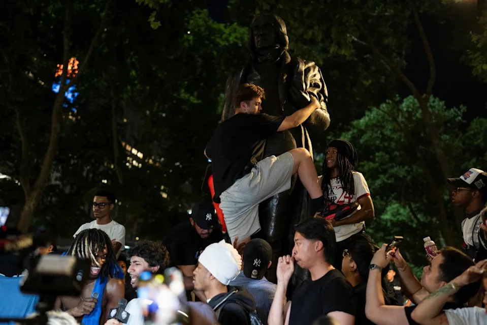 A fan climbs a pole in Bryant Park after Game 5 of the NBA Finals. REUTERS