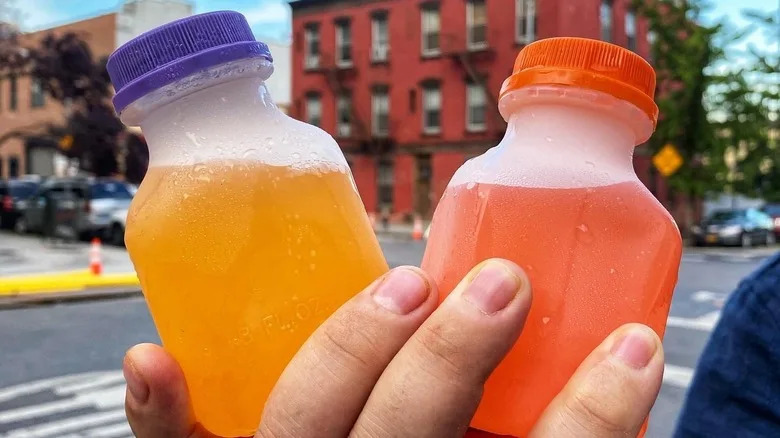 a hand holding two nutcracker cocktails in plastic bottles