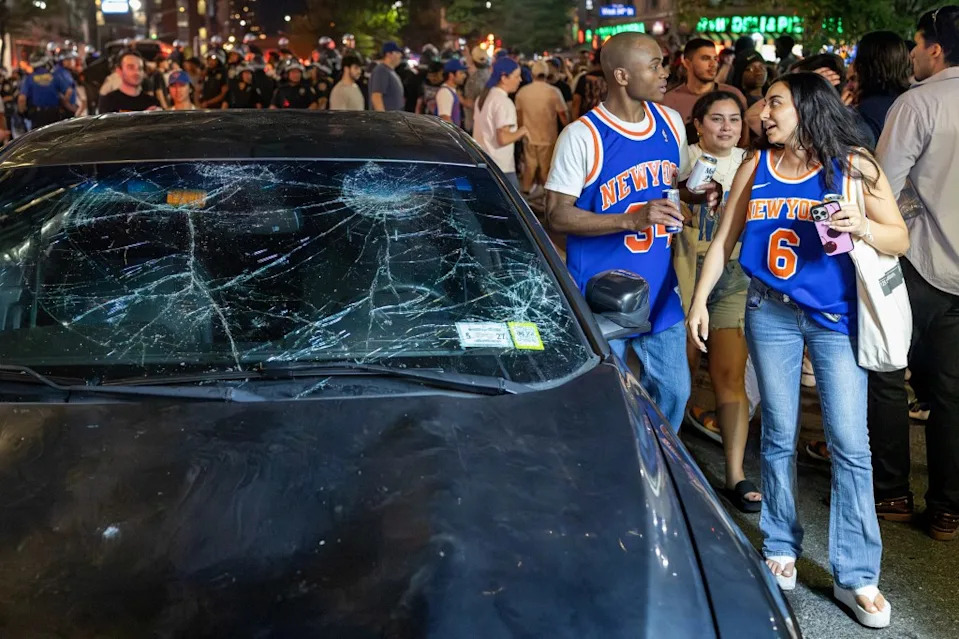 Knicks fans walk past a car that was damaged after people jumped on top of it on 9th Avenue. Aristide Economopoulos for NY Post
