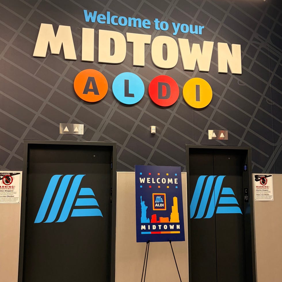 Interior of an Aldi store with a "Welcome to Midtown" sign and two elevators.