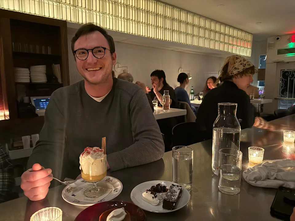 Man smiling with dessert in a restaurant