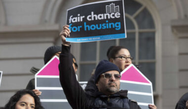A man holds a sign at a December 2022 rally in support of the Fair Chance for Housing bill.