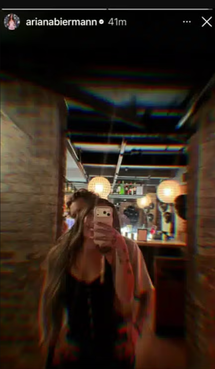 Person taking a mirror selfie in a dimly lit bar with hanging lights. Person taking a mirror selfie in a dimly lit bar with hanging lights.