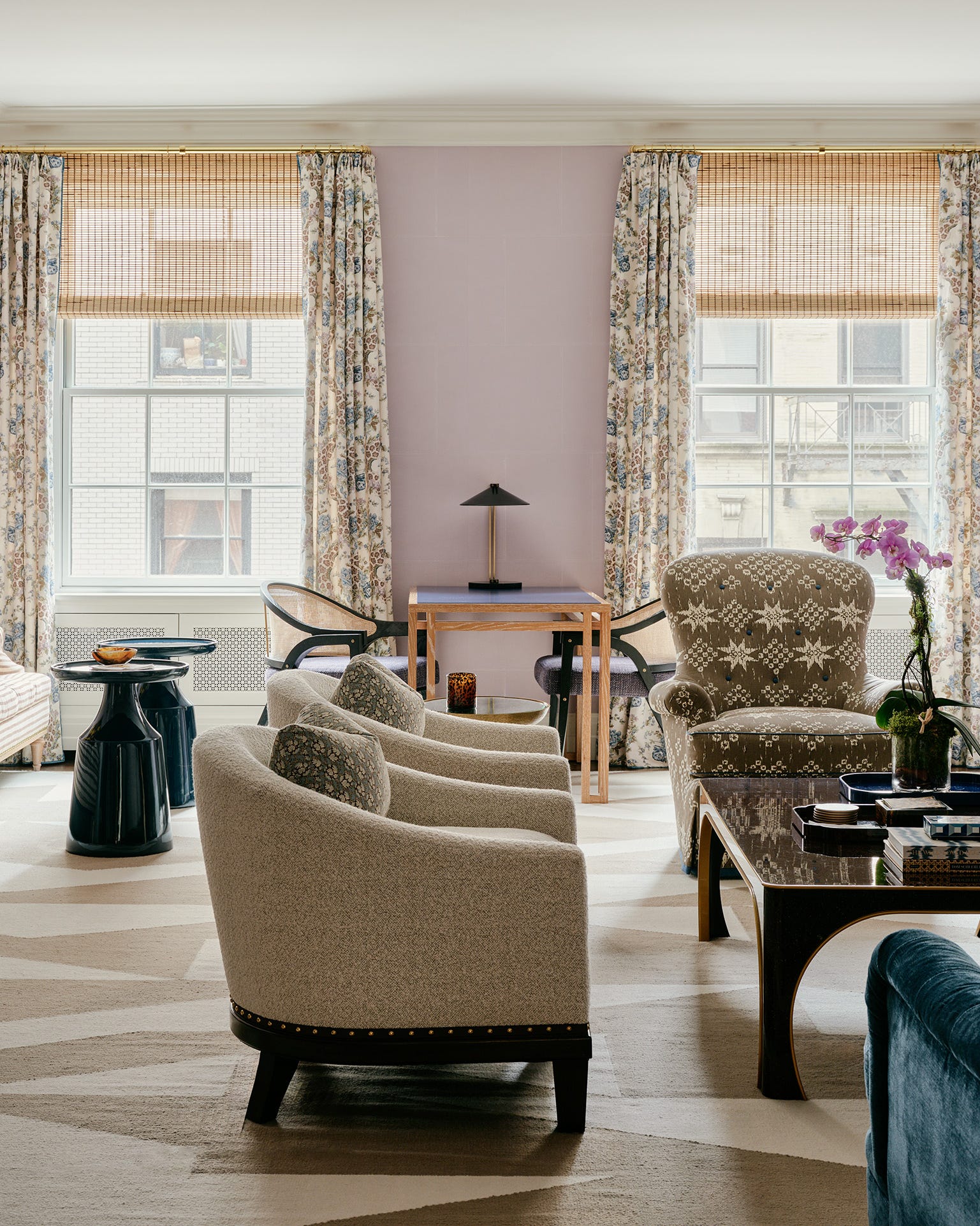 Elegant living room with plush chairs, sofa, fireplace, large mirror, and colorful decor.