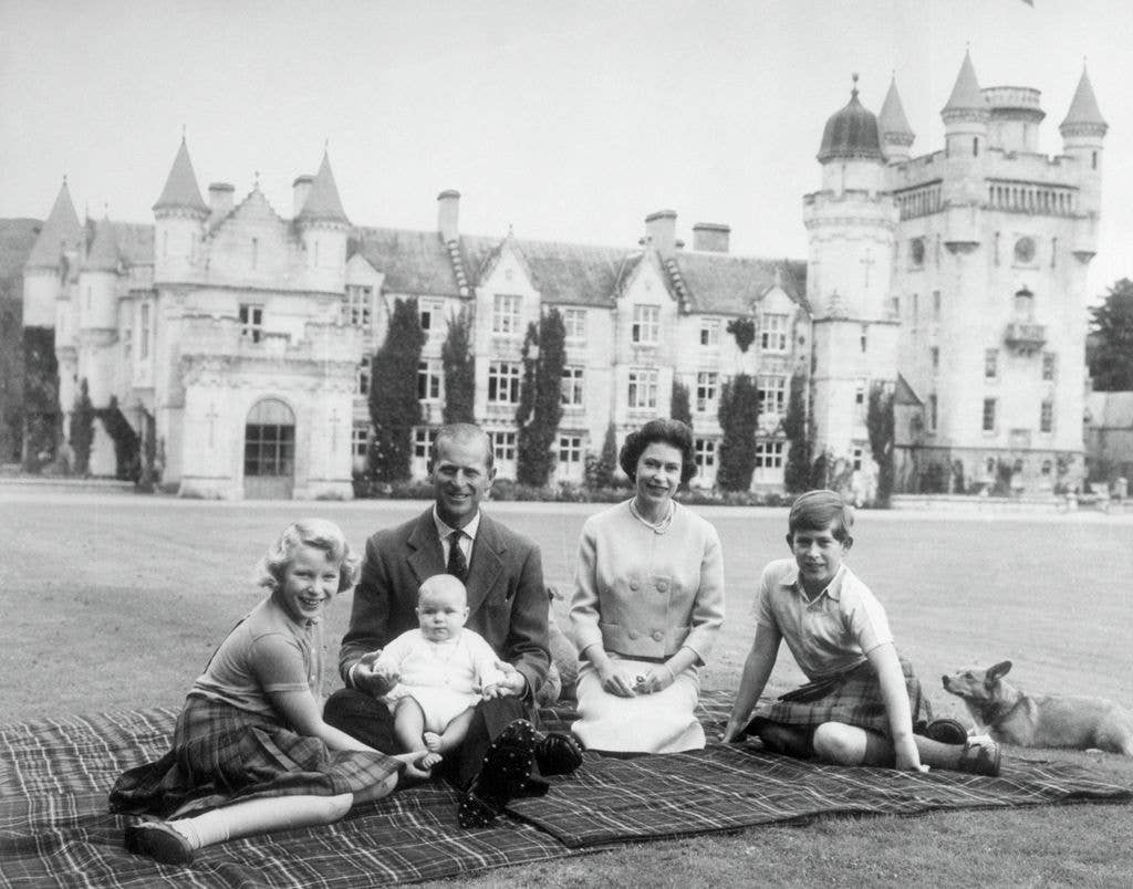 Queen Elizabeth II and Prince Philip, Duke of Edinburgh with their children, Prince Andrew (centre), Princess Anne (left) and Charles, Prince of Wales sitting on a picnic rug outside Balmoral Castle 
