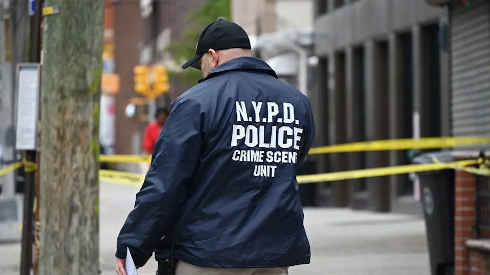 nypd officer walks through a crime scene
