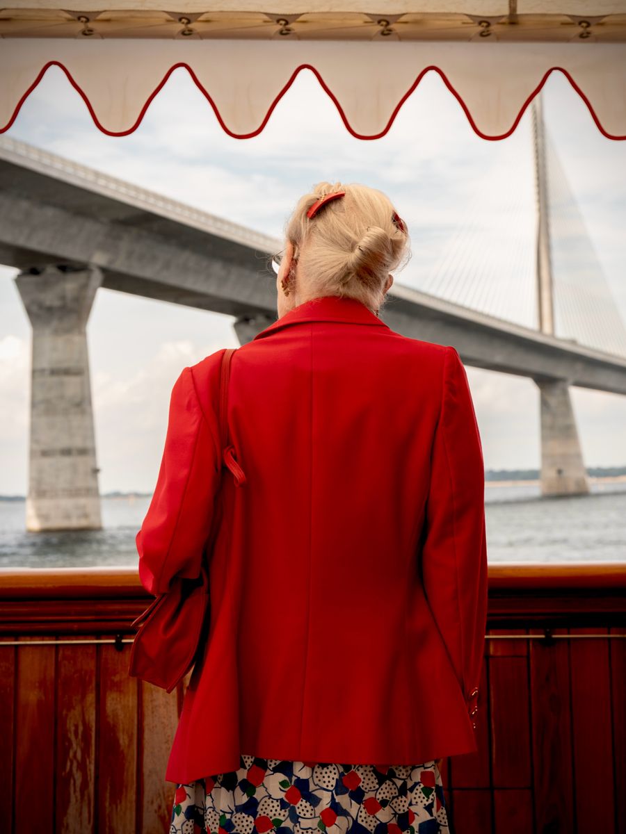 The former Danish monarch looked elegant in a vibrant red blazer and printed dress for the meaningful royal engagement.