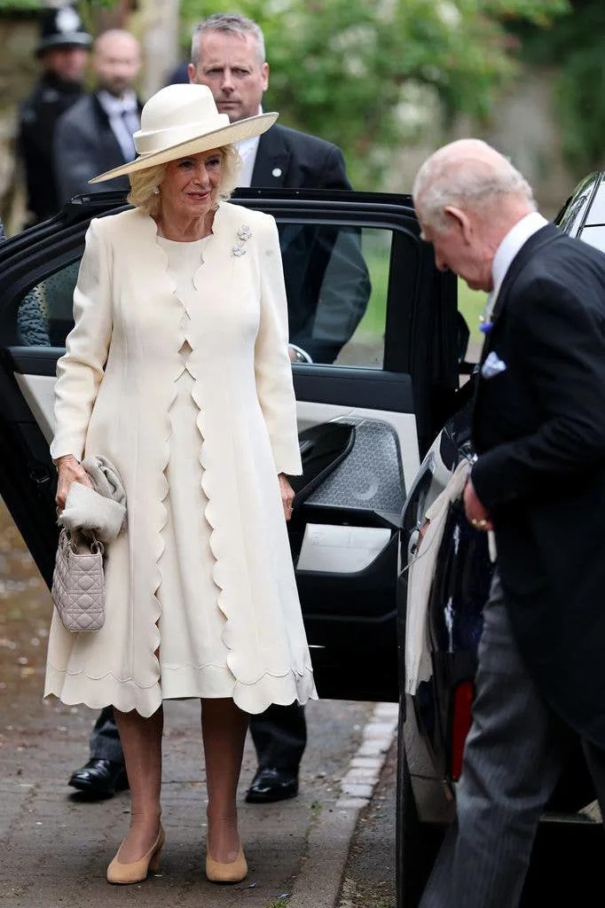 Queen Camilla and King Charles III waiting beside a car