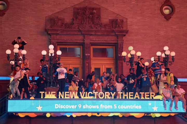 New York Knicks fans climb on top of the New Victory Theater marquee in Times Square on Saturday. (AP Photo/Andres Kudacki)