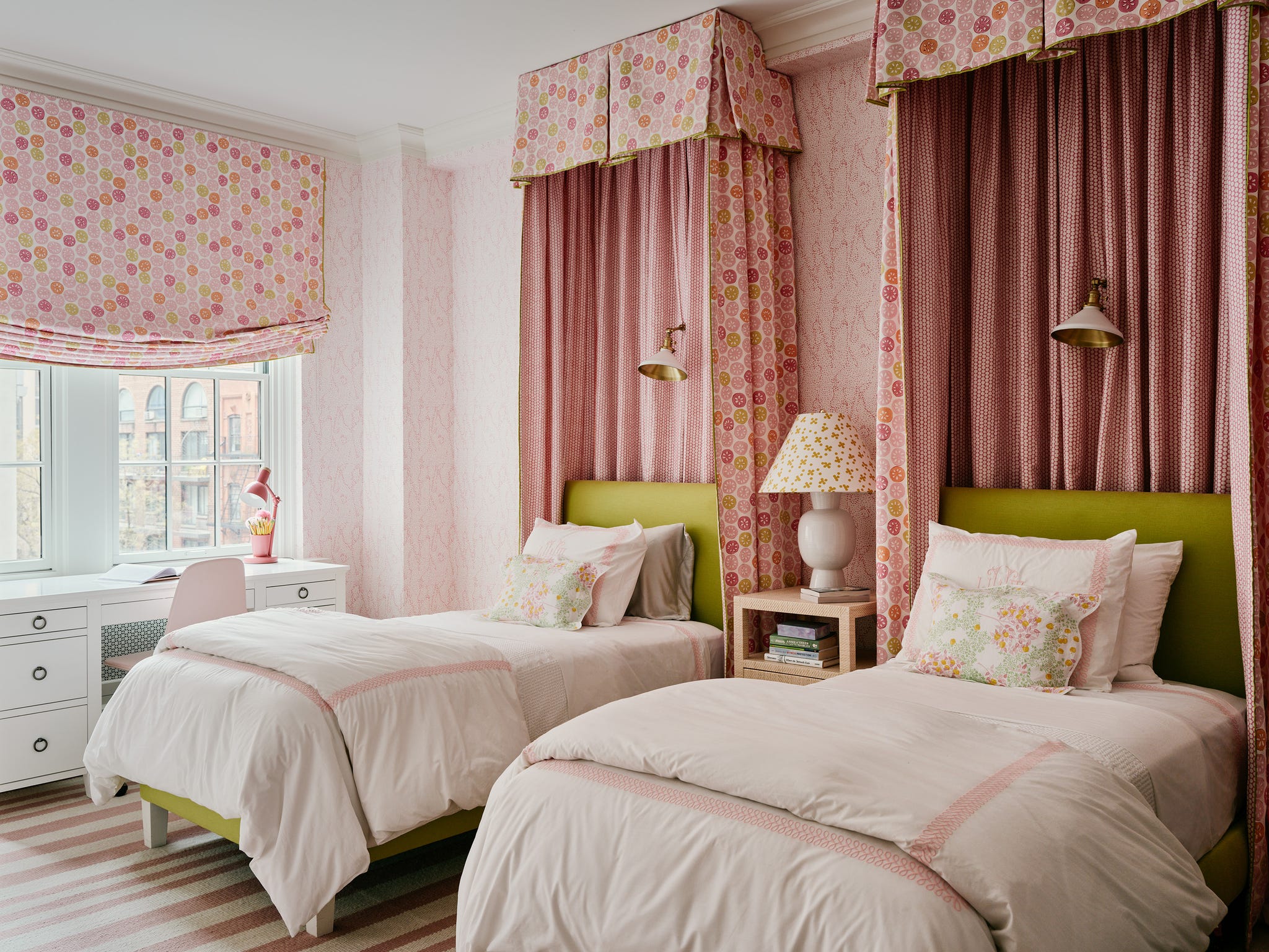 Twin beds in a pink-themed bedroom with floral curtains and desk.