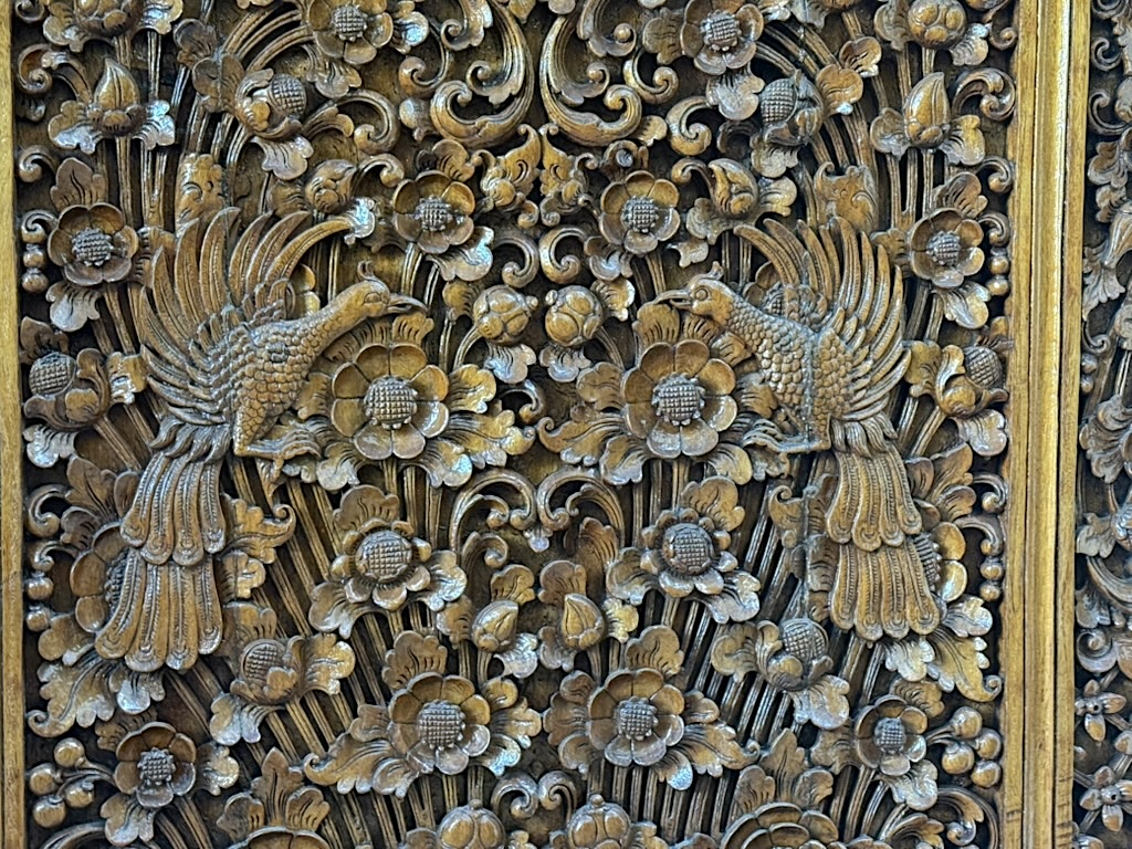 Intricate wooden carving featuring two birds amidst floral patterns.