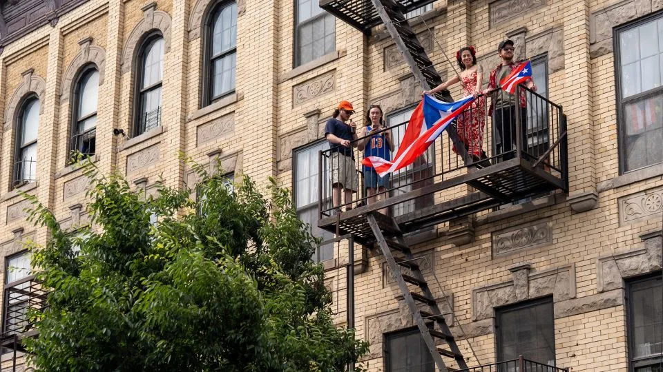 People watch the Puerto Rican Day celebration from a fire escape in Bushwick. - David Dee Delgado for CNN