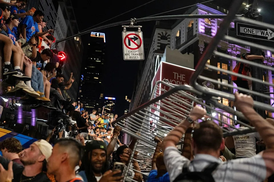 Knicks fans sitting on top of a school bus watch as others dismantle a barrier set up in Times Square. REUTERS