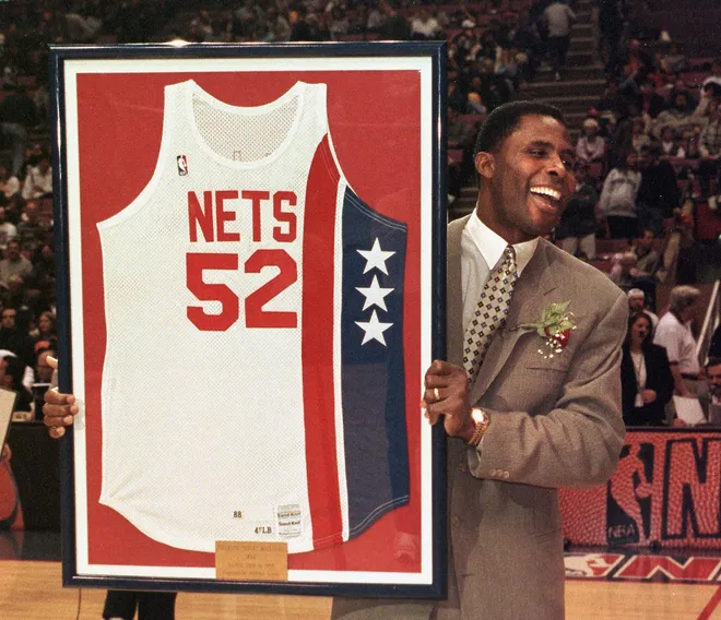Former NBA player Charles "Buck" Williams holds his New Jersey Nets jersey which was retired by the Nets during halftime of their game against the New York Knicks. Williams played for both the Nets and Knicks during his career as well as the Portland Trailblazers. AFP PHOTO/Matt CAMPBELL (Photo by MATT CAMPBELL / AFP) (Photo by MATT CAMPBELL/AFP via Getty Images)