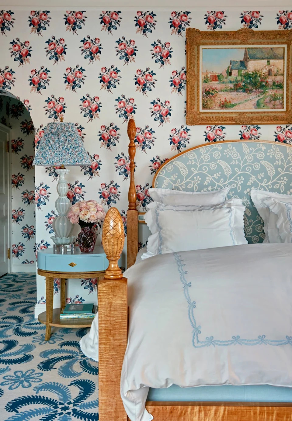 Bedroom with floral wallpaper and wood bed with white and blue linens