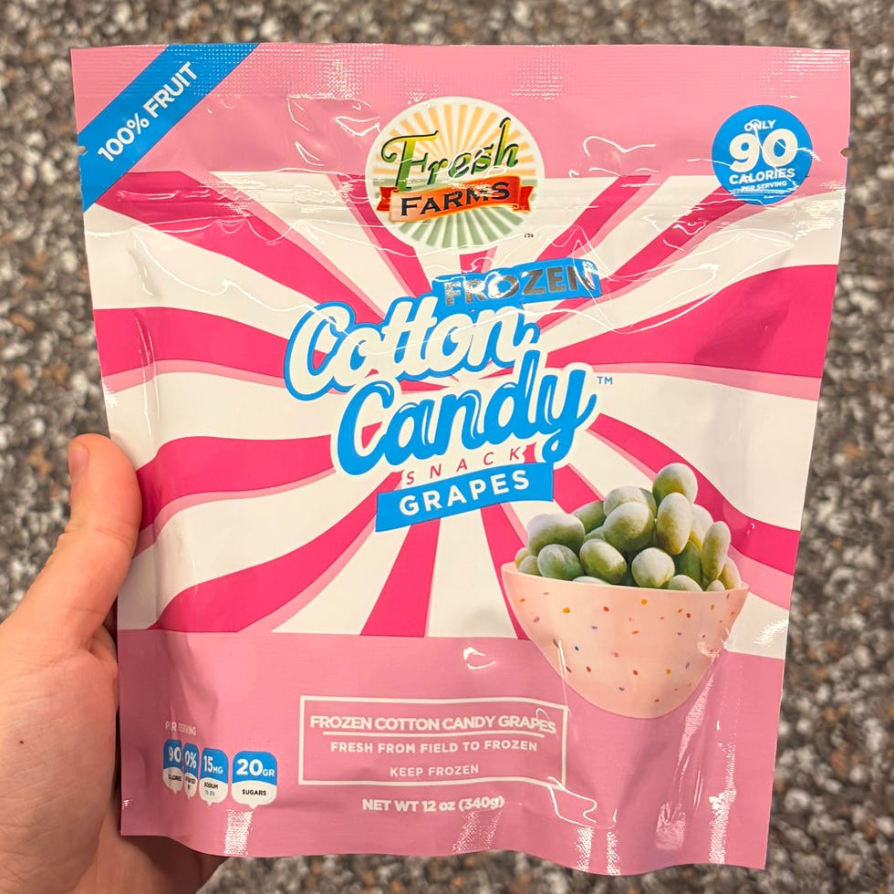 Person holding a bag of Fresh Farms Frozen Cotton Candy Grapes.