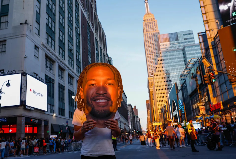 A Knicks fan holds a giant cutout of Knicks guard Jalen Brunson.