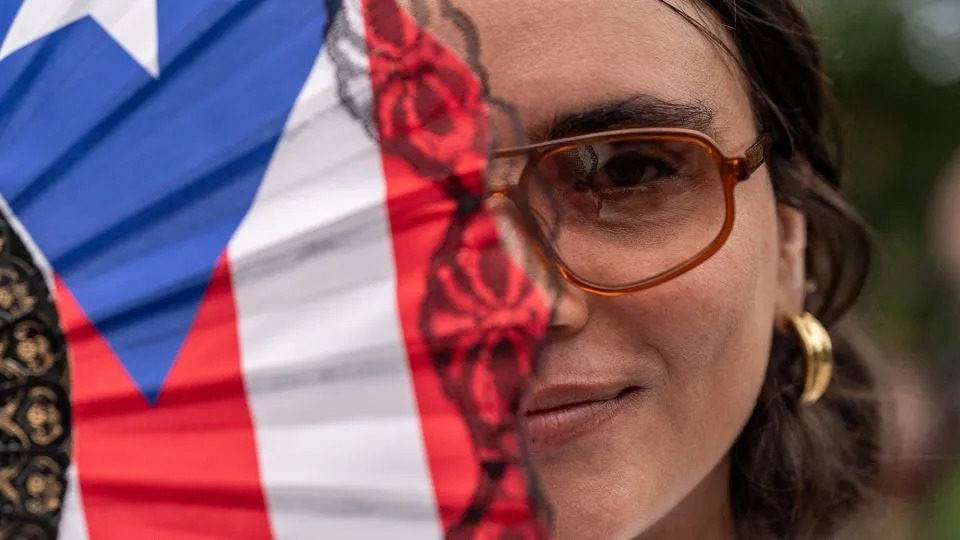 The Puerto Rican flag transforms into the ultimate accessory for the celebratory weekend. Here, a festival-goer carries a flag-emblazoned fan. - David Dee Delgado for CNN