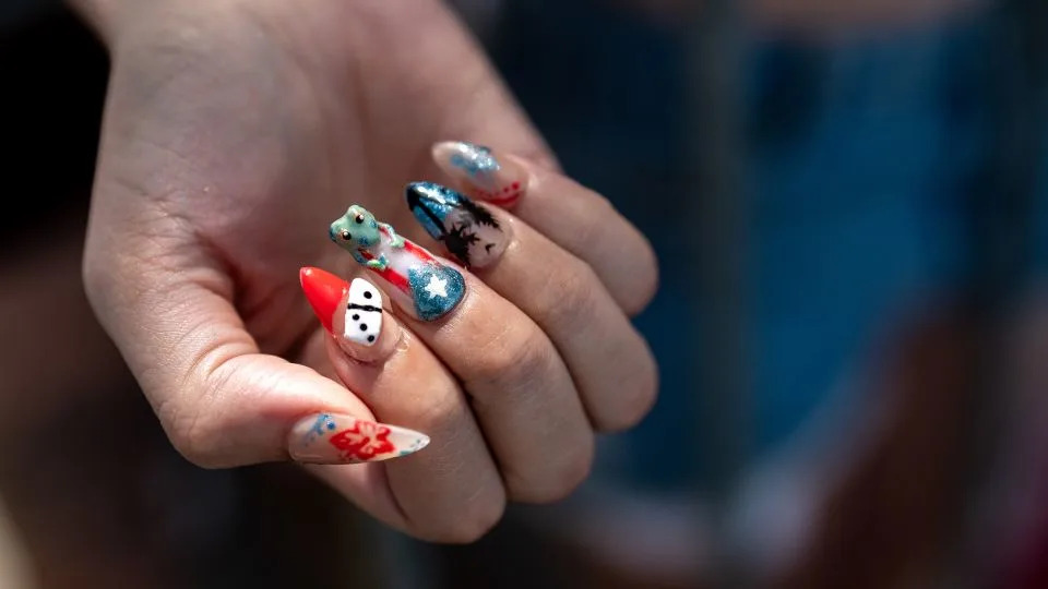 A festival-goer shows their Puerto Rico-themed custom nails, featuring dominos, the flor de maga, and the coqui frog. - David Dee Delgado for CNN
