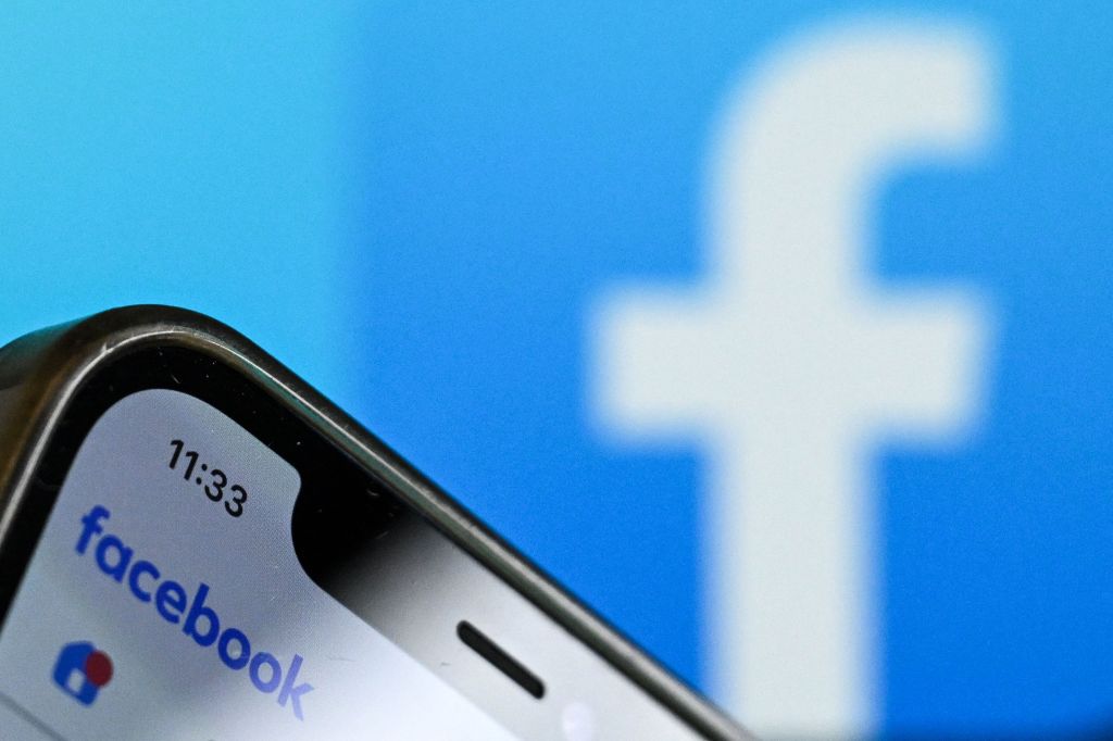 A smartphone displaying the Facebook logo and "facebook" against a blurred blue background with a large white Facebook "f" logo.