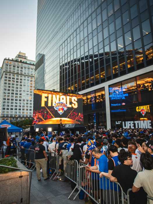 large group of people watching a TV screen outdoors