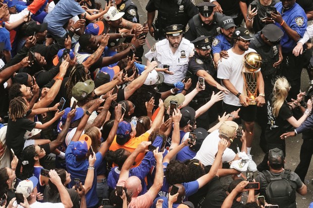 New York Knicks; Jalen Brunson, upper right, holds the Larry O'Brien Championship Trophy as he makes his way past fans during the NBA basketball team's championship ticker-tape parade along Broadway in New York's "Canyon of Heroes," Thursday, June 18, 2026. (AP Photo/Richard Drew)