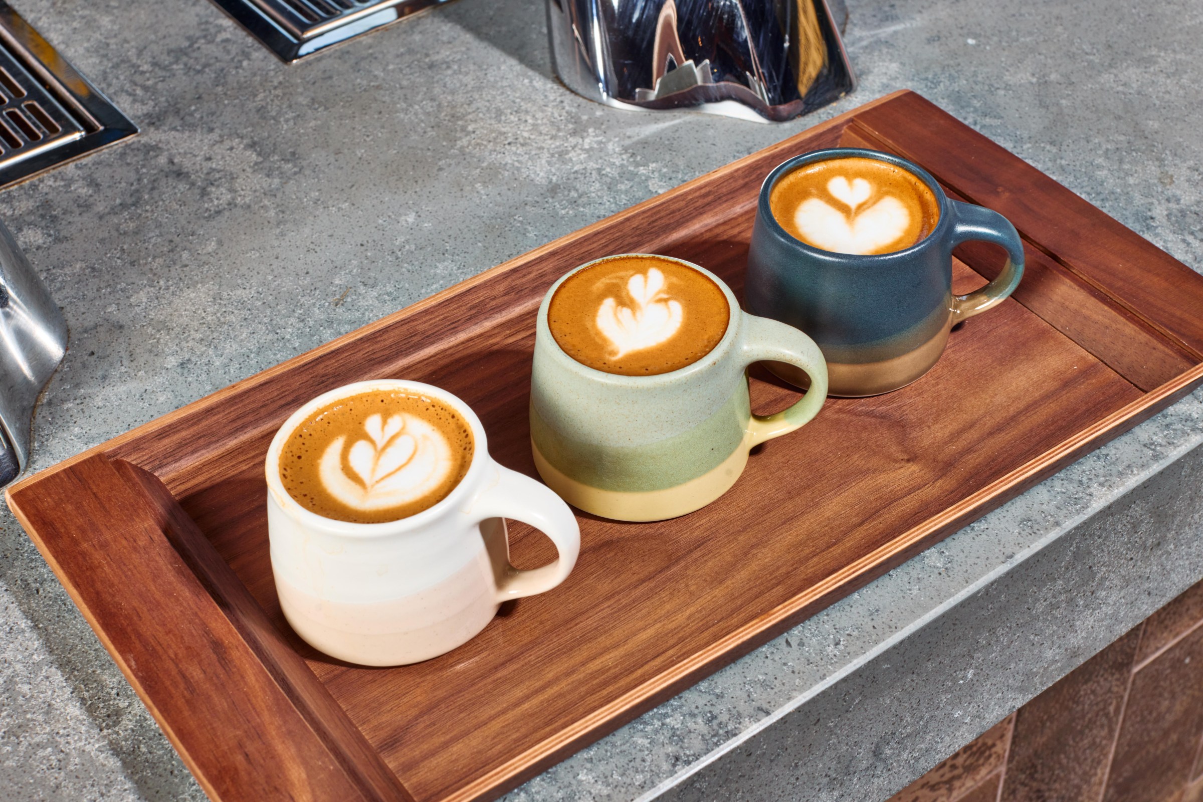 A bunch of lattes on a wooden tray.