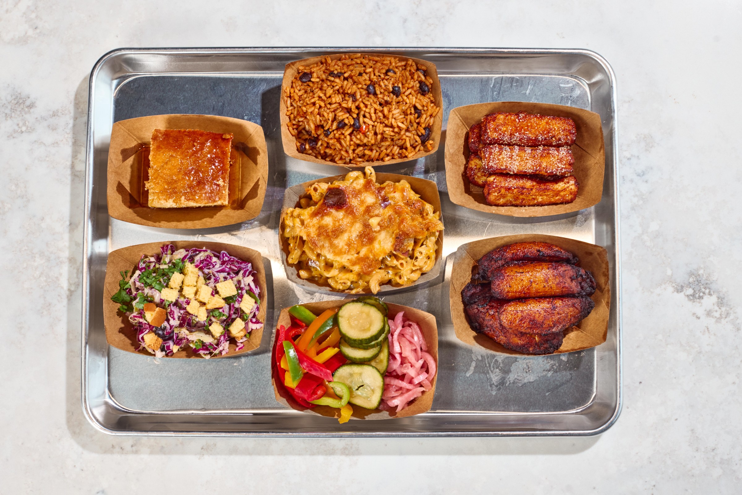 A bunch of food in cardboard boats on a tray.