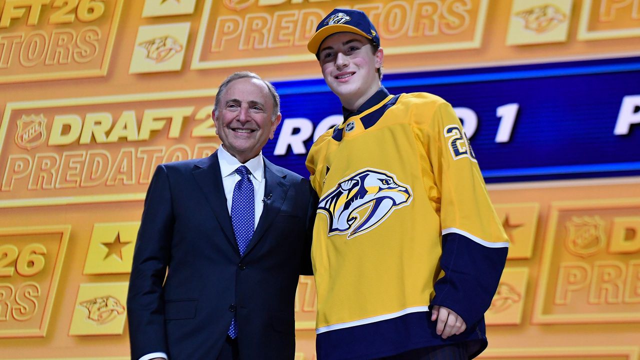 Thomas Bleyl, right, stands with NHL Commissioner Gary Bettman after being drafted by the Nashville Predators during the NHL hockey draft Friday, June 26, 2026, in Buffalo, N.Y. (AP Photo/Adrian Kraus)