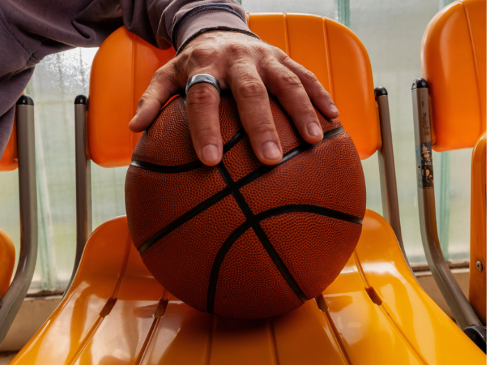 Man's hand holding basketball and wearing Oura Ring