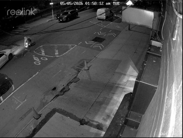 Surveillance footage shows a person descending into a sewer on a street in New York.