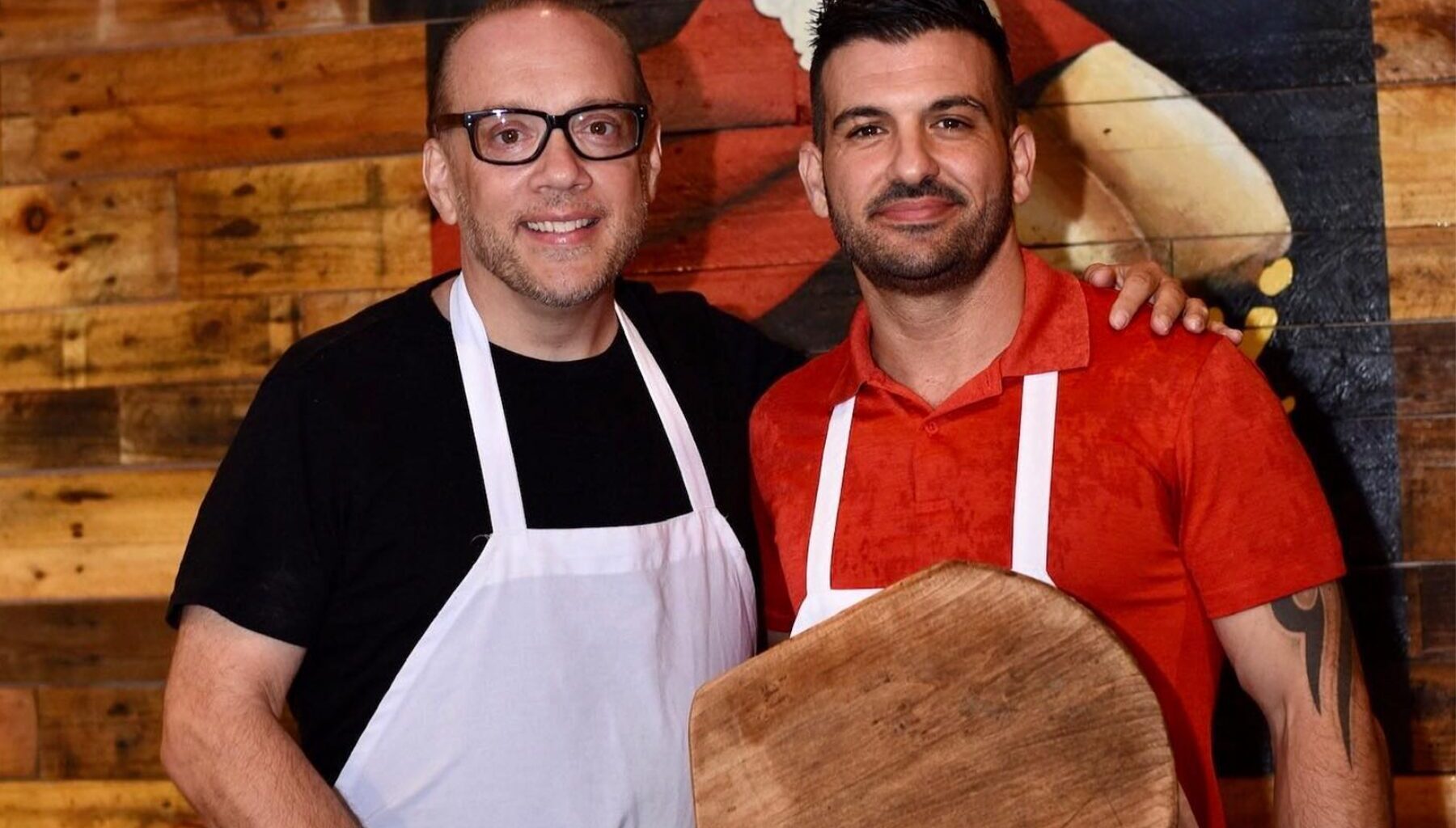 Bruno DiFabio and Mike Bennici, wearing aprons and holding a pizza pallet.