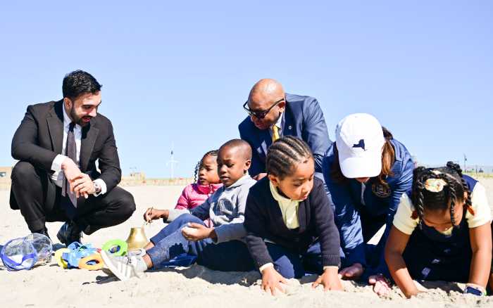 Mayor Zohran Mamdani, Governor Kathy Hochul and Queens Borough President Donovan Richards play in the sand at Rockaway Beach with children from nearby Sheldon R. Weaver Child Care Center in a Queens school district selected for the first cohort of free 2-K seats. 