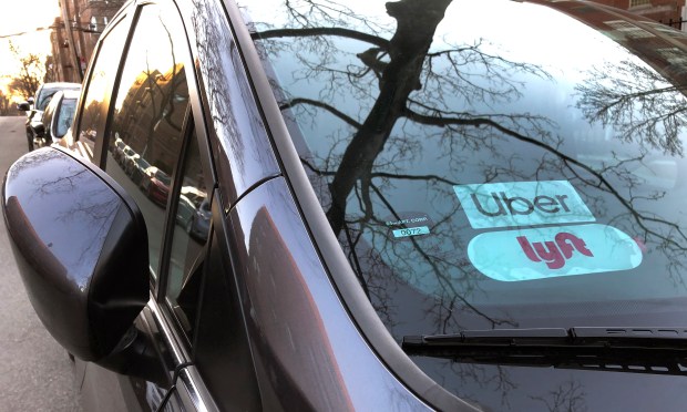 Uber and Lyft signs in the windshield of a car in Queens.