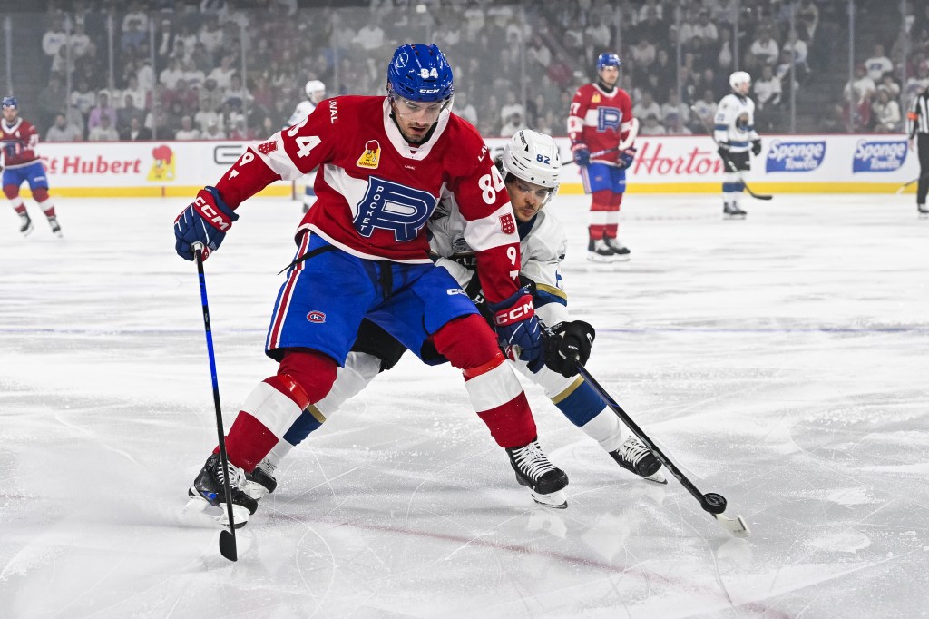 Laval Rocket defenceman William Trudeau (84) defends the puck against Cleveland Monsters left wing Mikael Pyyhtia (82) 