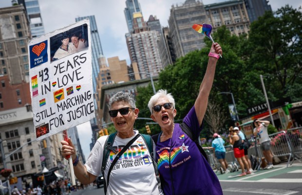 A couple marches holding a poster reading "43 years in love, still marching for justice" during the annual New York City Pride March in New York on June 28, 2026. (Photo by kena betancur / AFP via Getty Images)