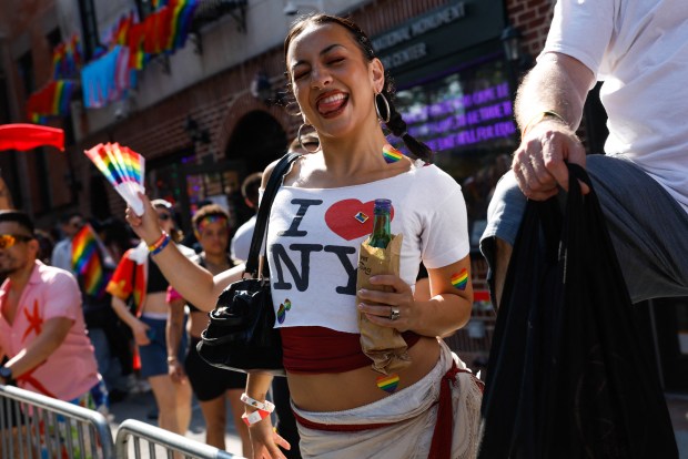 People stand outside the Stonewall Inn as they watch the annual New York City Pride March in New York on June 28, 2026. (Photo by kena betancur / AFP via Getty Images)
