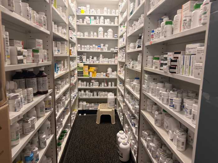 Fully stocked shelves of prescriptions behind the counter at Pilgrim Pharmacy.