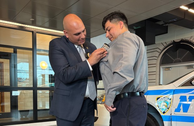 NYPD graduate Christian Leon, right, receives his shield on Tuesday, June 23, 2026, from Det. James Fares, who rescued him after a car crash in 2021. (Roni Jacobson / New York Daily News)
