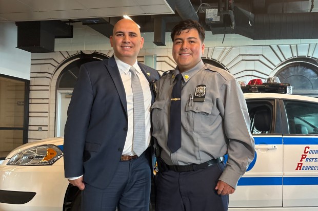 NYPD graduate Christian Leon, right, receives his shield on Tuesday, June 23, 2026, from Det. James Fares, who rescued him after a car crash in 2021. (Roni Jacobson / New York Daily News)