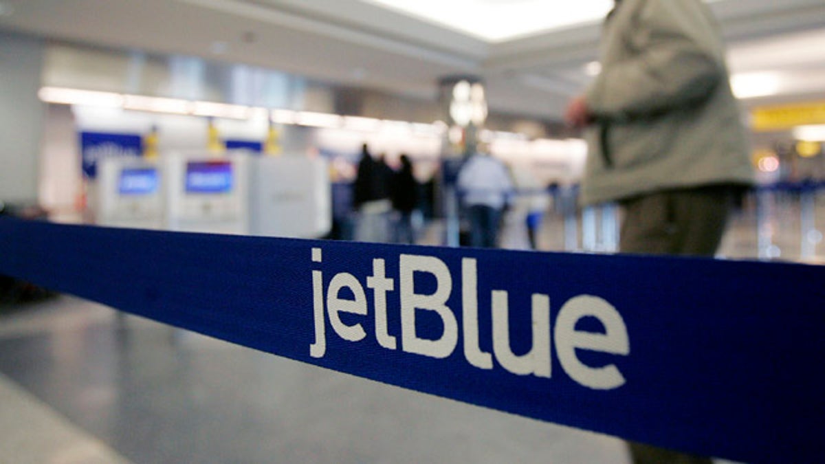FILE - In this Wednesday Feb. 1, 2006, file photo, a pedestrian makes his way to the e-ticket counter of JetBlue at New York's LaGuardia Airport. Starting in 2014, JetBlue, the all-coach airline, plans to offer 16 lie-flat seats on flights between New York and Los Angeles and San Francisco. Itâs the first time the egalitarian carrier will have a second class of service. (AP Photo/Frank Franklin II, File)