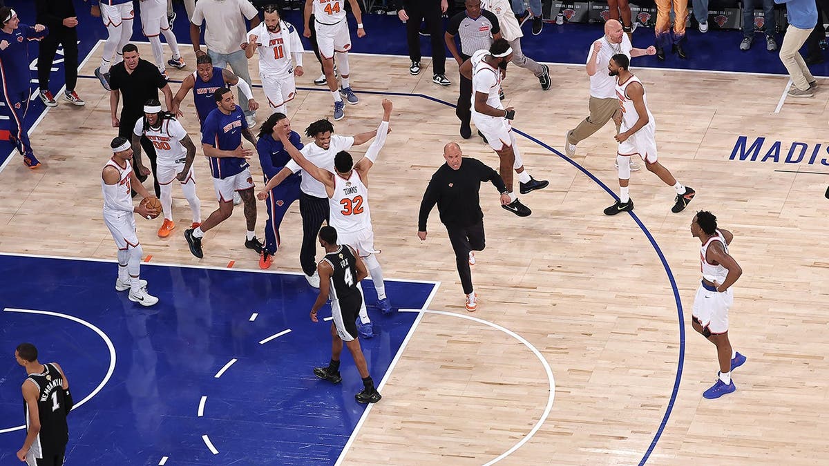 New York Knicks players celebrating on the basketball court at Madison Square Garden.