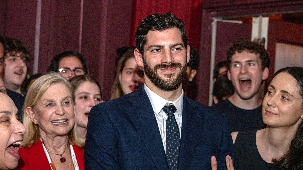 man in suit surrounded by supporters