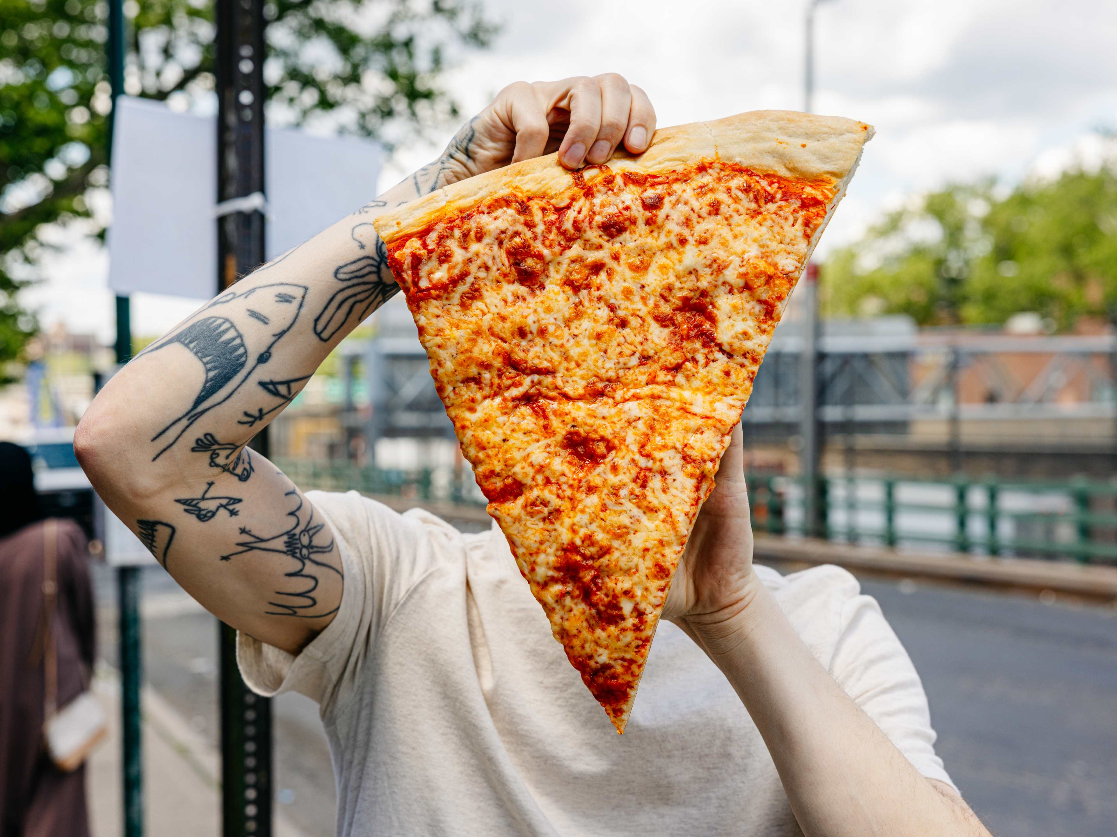 person holding up giant slice of pizza over their face
